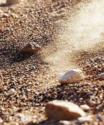 Sunlit beach with smooth pebbles on fine sand creating natural texture and warm lighting effect